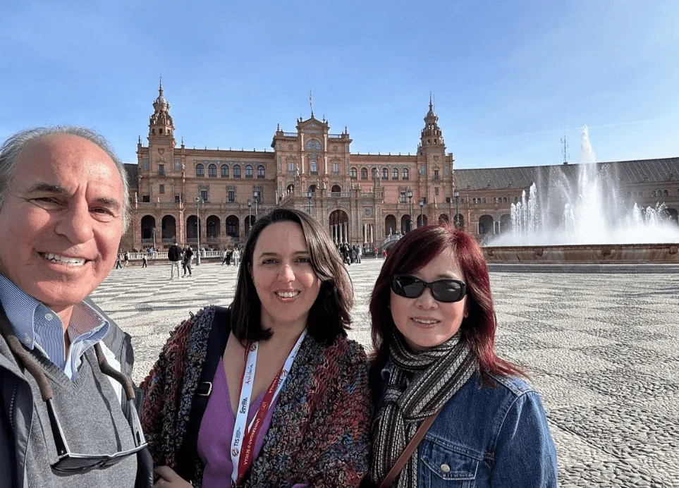 A private guide takes a selfie with two travelers by the fountain of Plaza de España in Seville