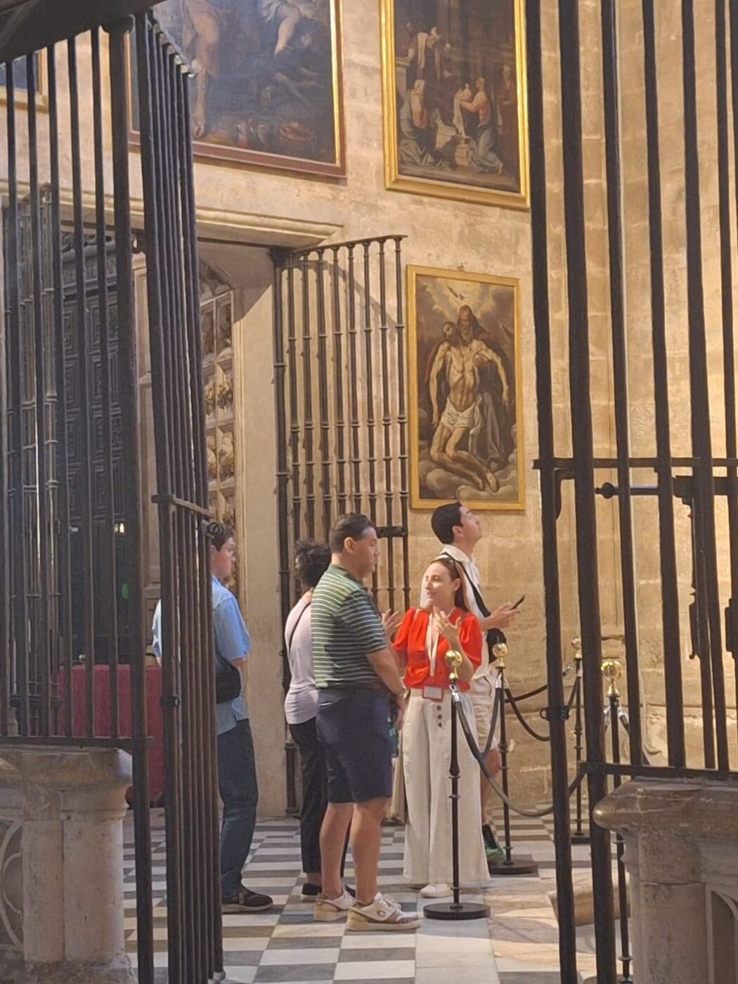 Guide explains paintings to visitors inside Seville Cathedral during a private tour