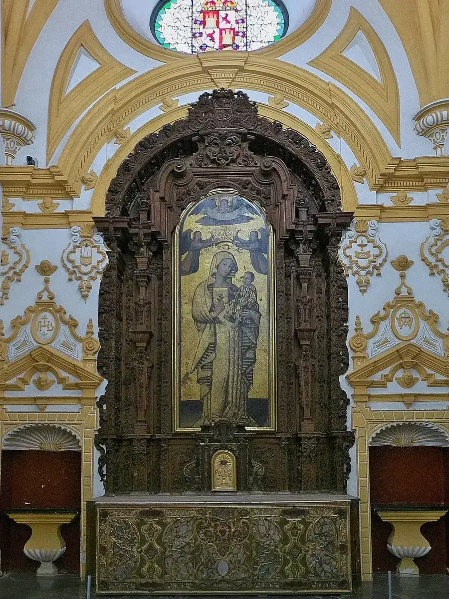 Gilded painting of the Virgin and Child in a carved wooden altarpiece beneath a baroque vault