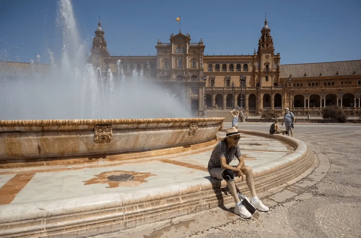 A traveler cools off by the Plaza de España fountain on a hot sunny day in Seville