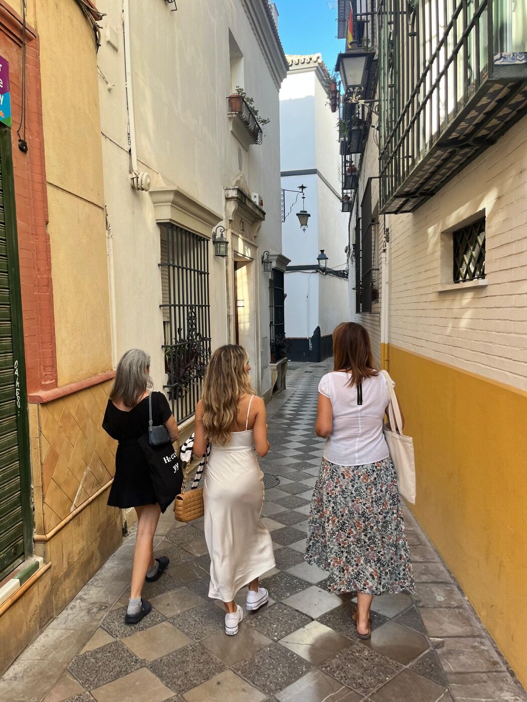 Three travelers walk a quiet, narrow lane in Seville's old town on a private tour away from mass tourism