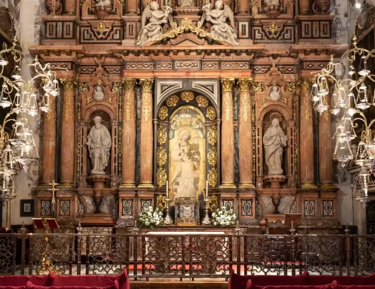 Altarpiece of the Virgin of La Antigua chapel in Seville Cathedral, framed by marble columns and hanging lamps