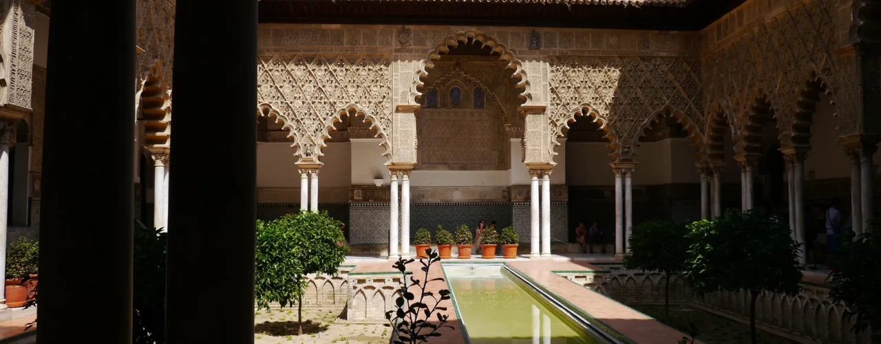 Patio de las Doncellas del Real Alcázar de Sevilla — arcos ornamentados y alberca